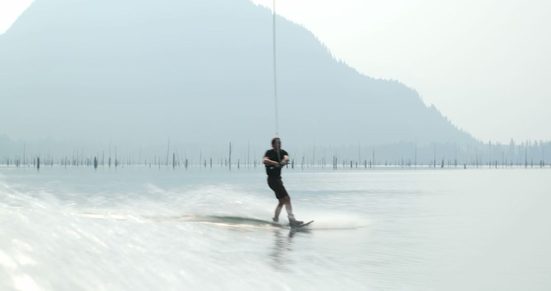 Young Man Wakeboarding on Lake with Scenic Mountain View - Free Images, Stock Photos and Pictures on Pikwizard.com