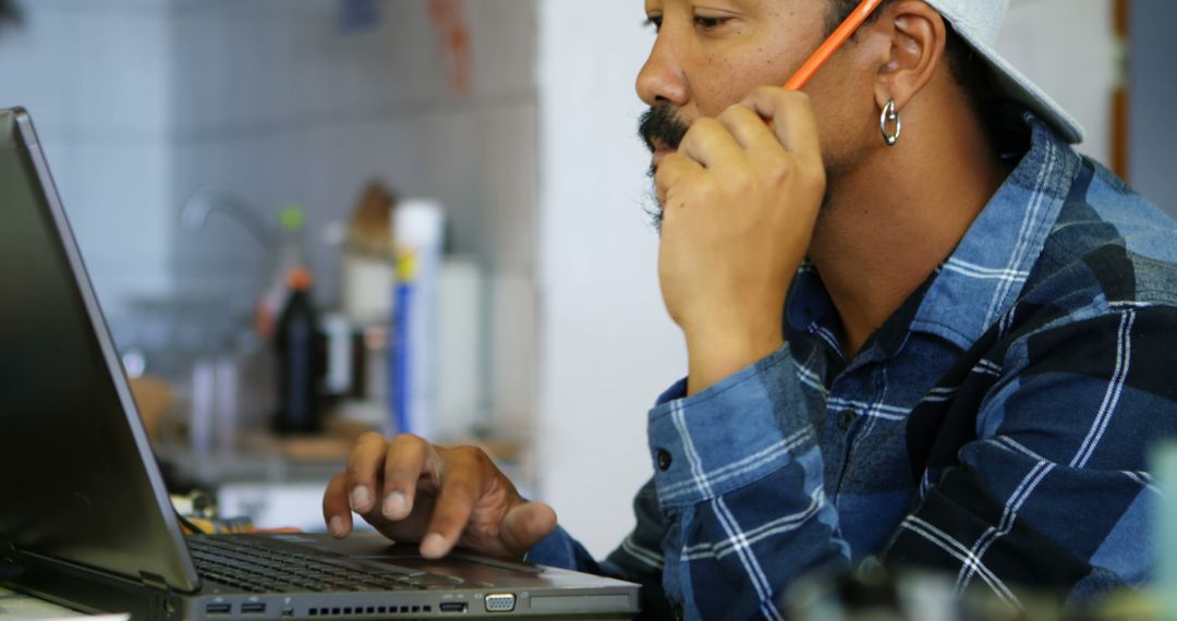 Man Focused on Laptop While Talking on Phone in Kitchen - Free Images, Stock Photos and Pictures on Pikwizard.com