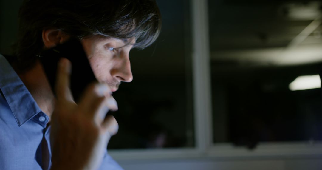 Exhausted Executive Talking on Phone at Desk Late at Night