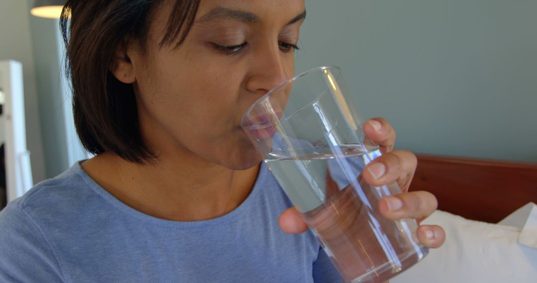 An African American woman is drinking a glass of water, with copy space - Free Images, Stock Photos and Pictures on Pikwizard.com