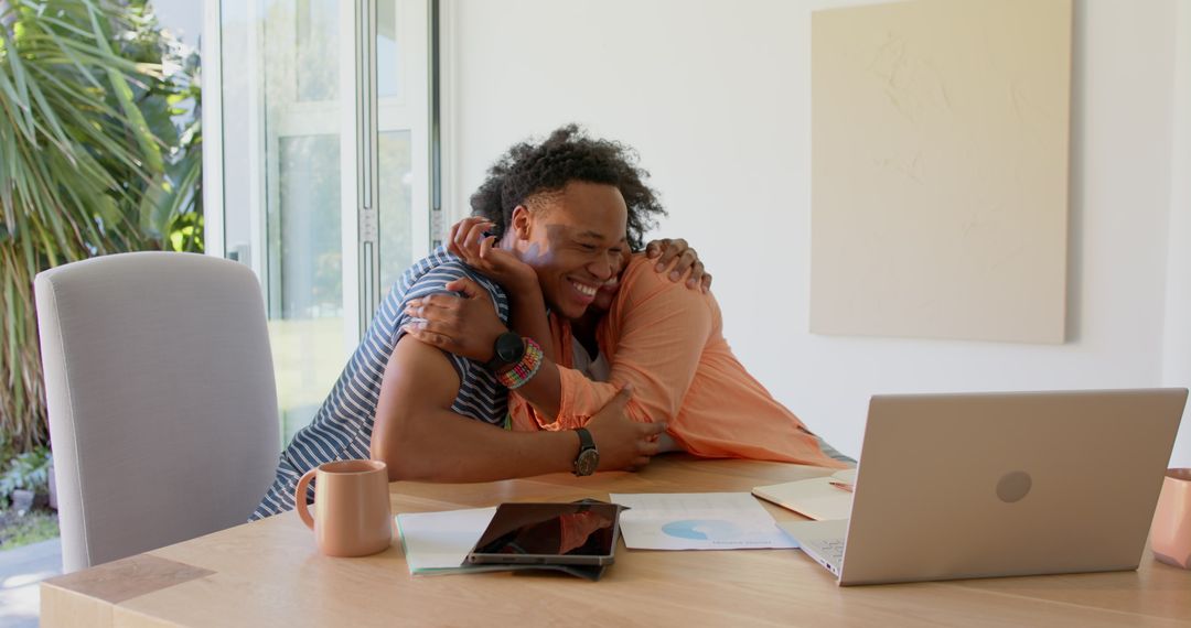 Happy Couple Embracing While Discussing Financial Documents Digitally