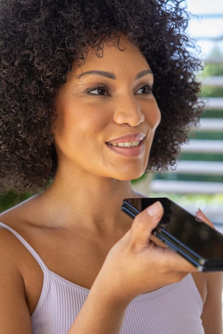 Smiling Woman Using Voice Command Technology Outdoors