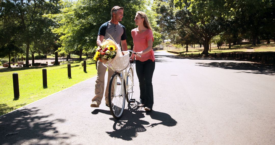 Couple Walking with Bicycle and Flowers in Park - Free Images, Stock Photos and Pictures on Pikwizard.com