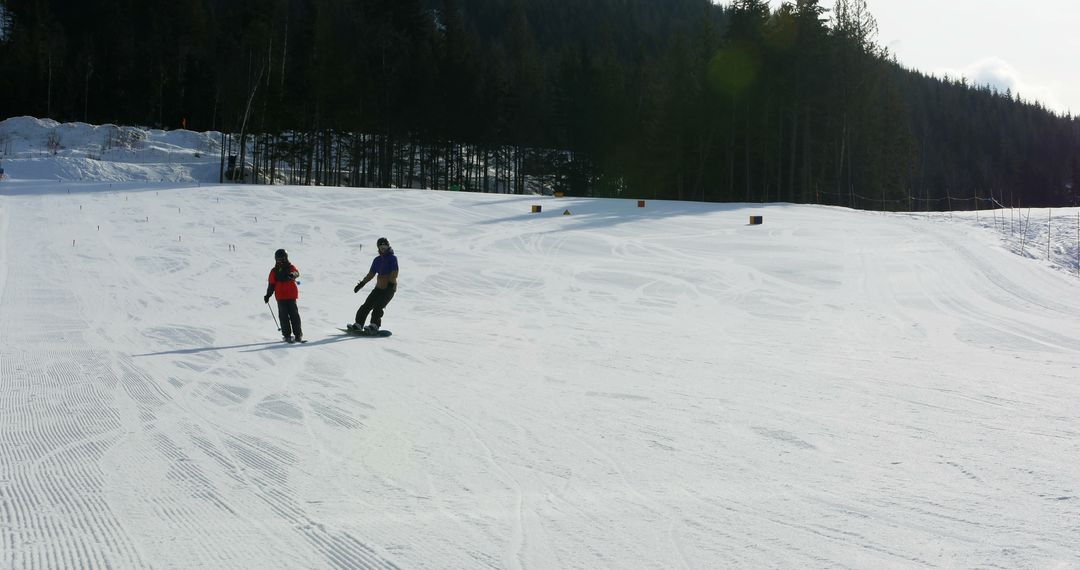 Two people, a young adult and a child, are snowboarding down a gentle slope, with copy space - Free Images, Stock Photos and Pictures on Pikwizard.com