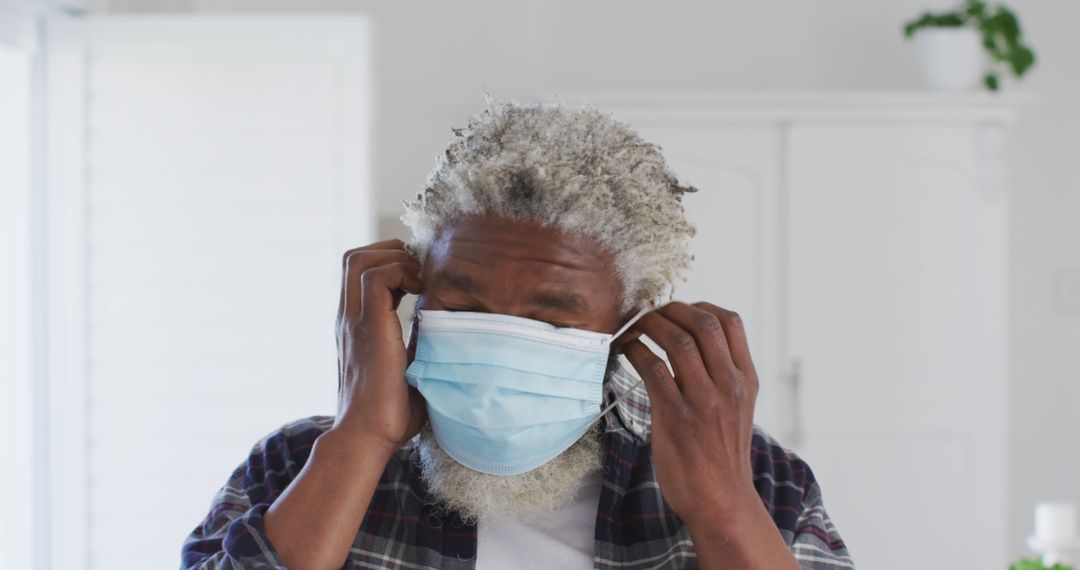 Older Man Adjusting Face Mask While Standing Indoors - Free Images, Stock Photos and Pictures on Pikwizard.com