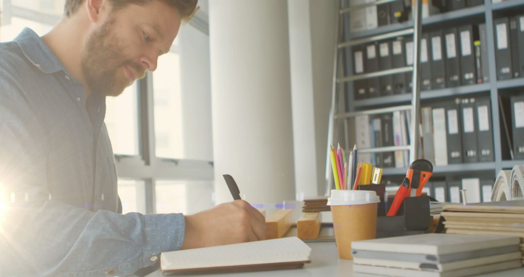 Focused Man Taking Notes in Bright Office Environment