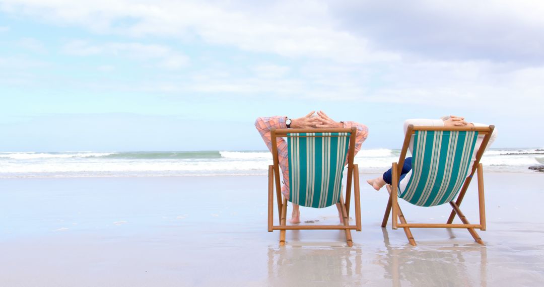 Senior Couple Relaxing on Beach in Deckchairs Overlooking Ocean