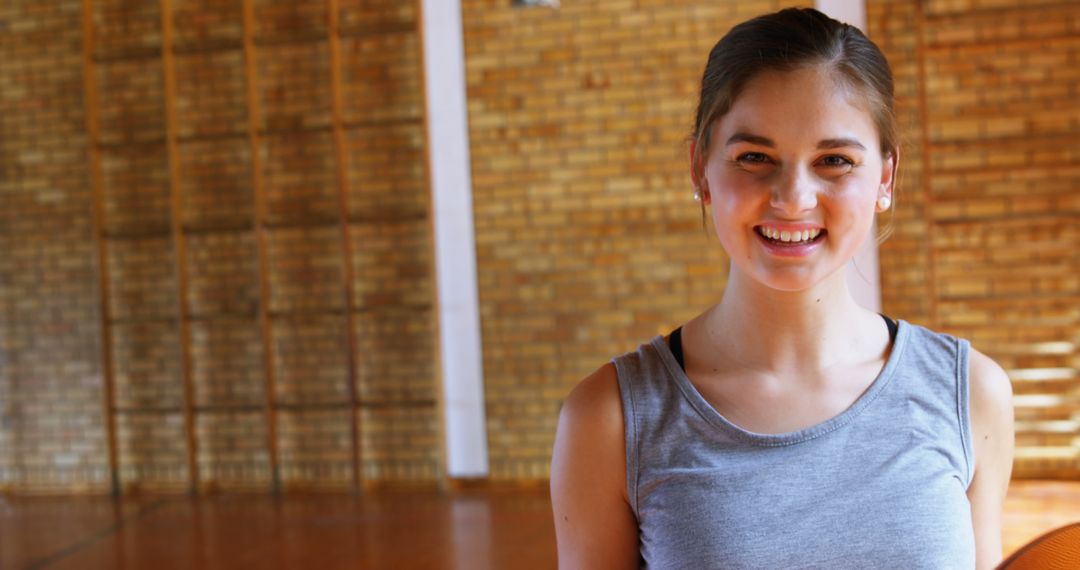 Smiling Young Woman in Gymnasium with Wooden Floor - Free Images, Stock Photos and Pictures on Pikwizard.com