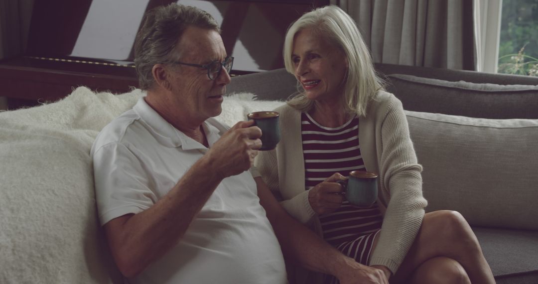 Senior couple relaxing on sofa with coffee mugs - Free Images, Stock Photos and Pictures on Pikwizard.com