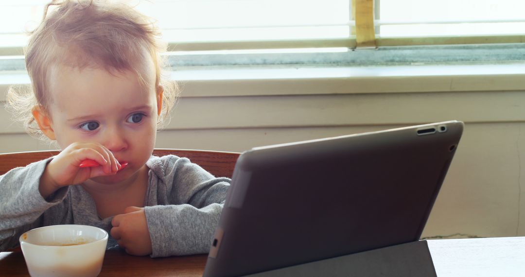 Toddler Using Tablet While Eating Cereal at Table - Free Images, Stock Photos and Pictures on Pikwizard.com