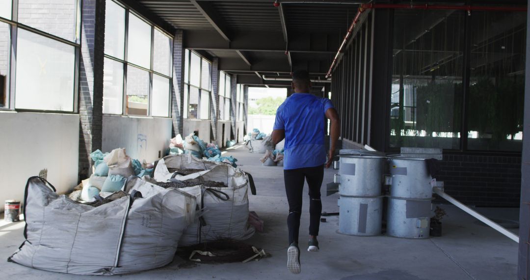 Man Running in Industrial Warehouse with Construction Materials - Free Images, Stock Photos and Pictures on Pikwizard.com