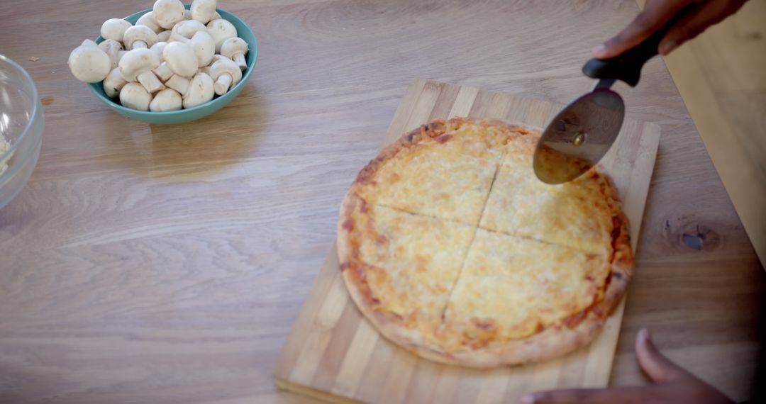 Person Cutting Cheese Pizza on Wooden Board with Mushrooms Nearby - Free Images, Stock Photos and Pictures on Pikwizard.com