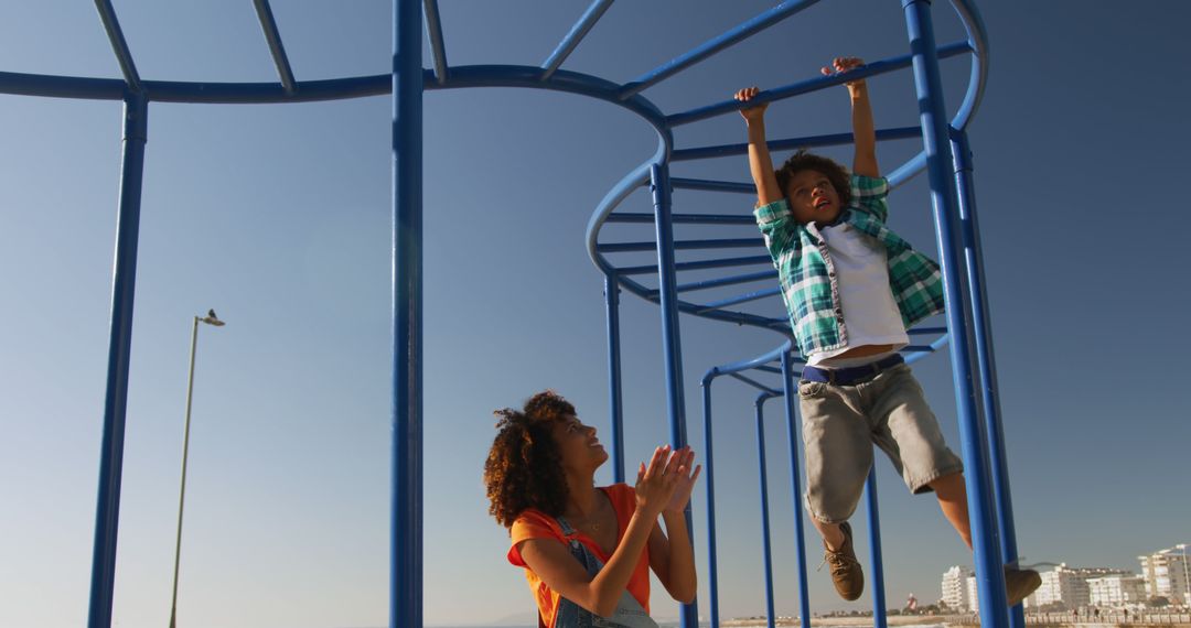 Mother Encouraging Child on Monkey Bars at Urban Playground - Free Images, Stock Photos and Pictures on Pikwizard.com