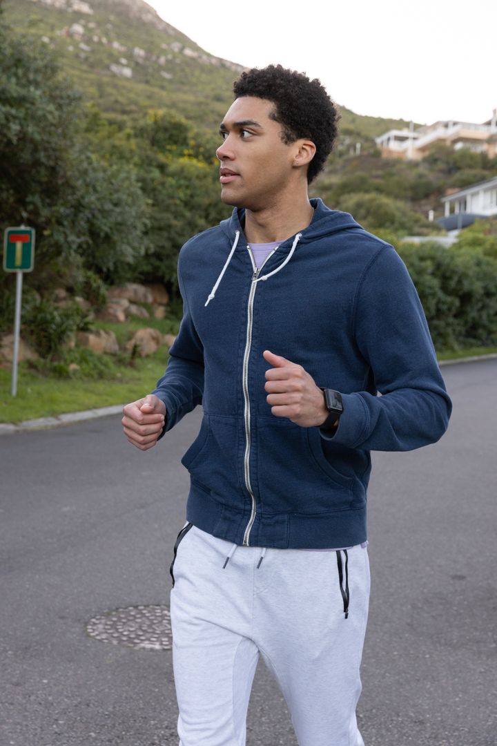 Man Running on Scenic Hillside Road Wearing Smartwatch