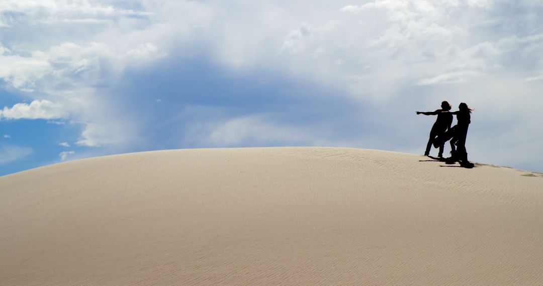 Couple Exploring Majestic Desert Dune on Bright Day