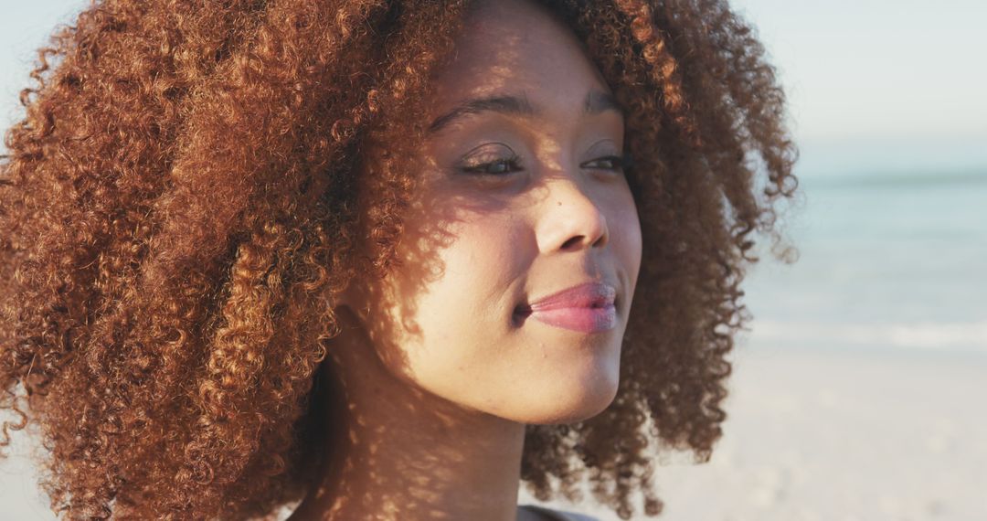 Confident Woman with Curly Hair Enjoying Beach Sunset - Free Images, Stock Photos and Pictures on Pikwizard.com