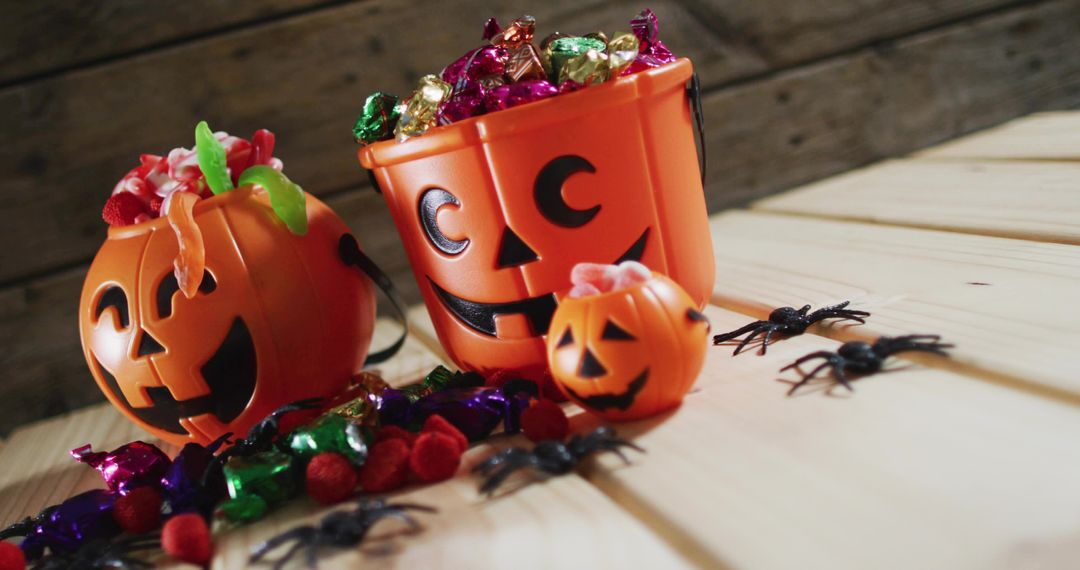 Jack-O'-Lantern Candy Buckets Overflowing with Foil Chocolates on Rustic Wood Table Autumn