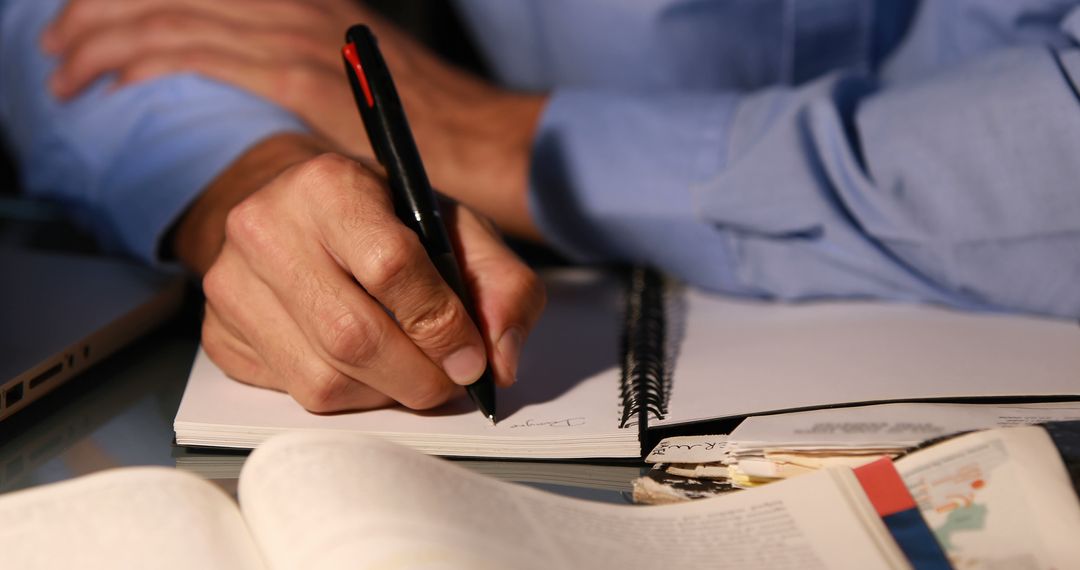 Person Writing in Notebook at Desk with Open Book - Free Images, Stock Photos and Pictures on Pikwizard.com