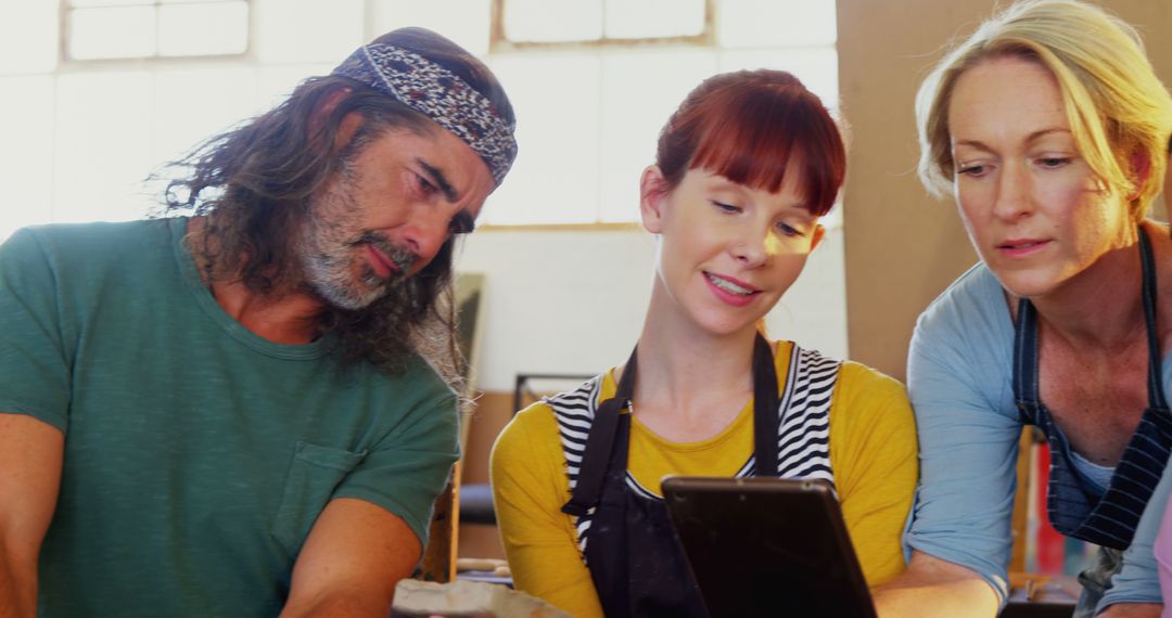 Creative Team Collaborating Reviewing Designs on Tablet