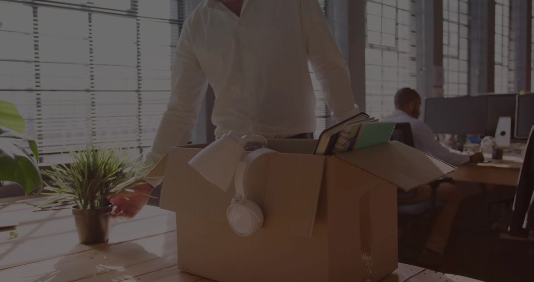 Office Worker Packing Belongings in Cardboard Box on Desk