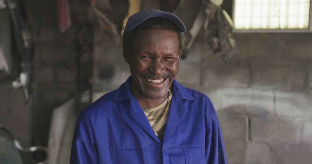 Mechanic Laughing in Workshop Wearing Blue Uniform and Cap - Free Images, Stock Photos and Pictures on Pikwizard.com