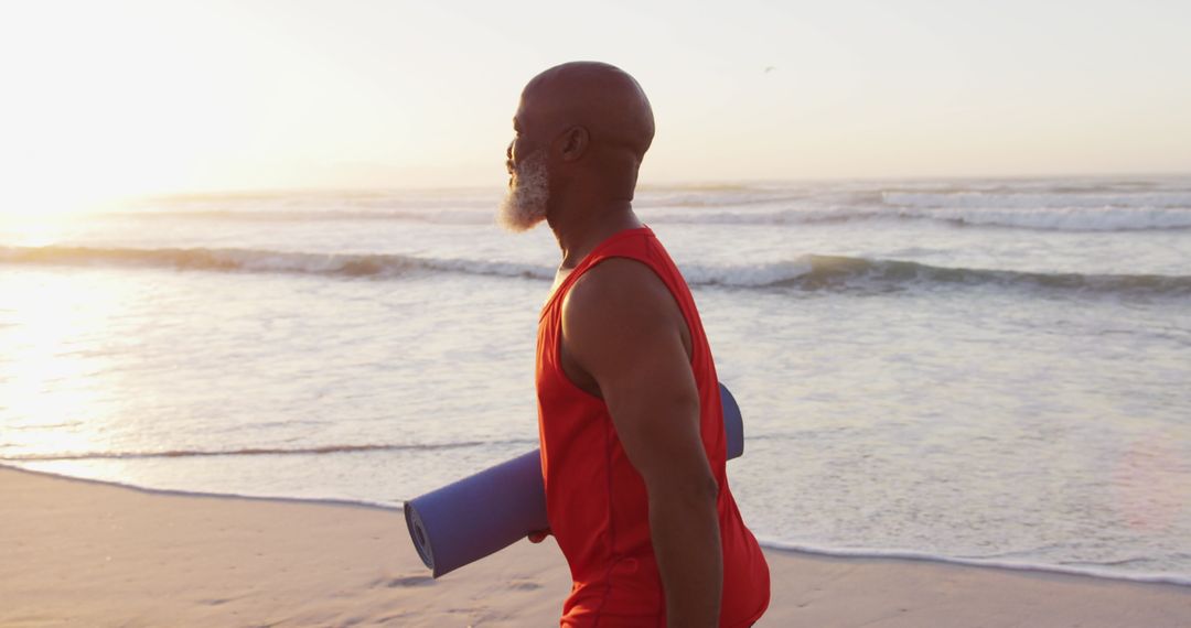 Senior Man Walking on Beach with Yoga Mat at Sunrise - Free Images, Stock Photos and Pictures on Pikwizard.com