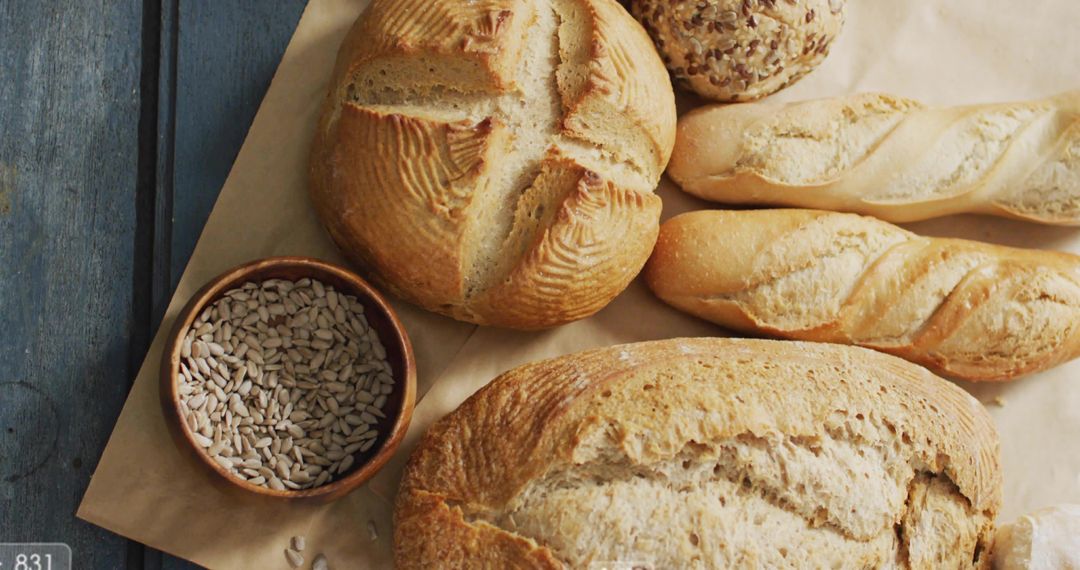 Rustic artisan bread assortment on parchment with seeded rolls, baguettes, boule, seeds