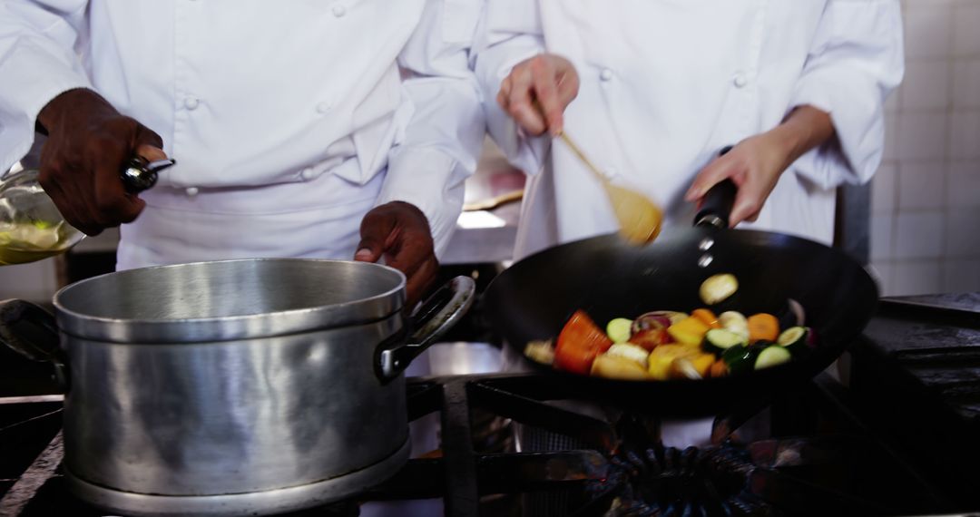 Chefs Skillfully Preparing Dishes Together in Professional Kitchen