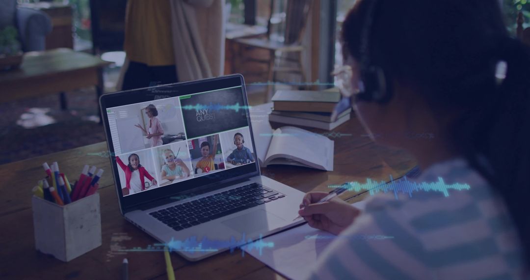 Child writing in notebook during virtual classroom session with laptop and headphones