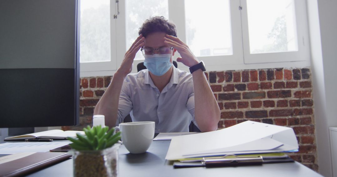 Frustrated Businessman Wearing Face Mask Working at Office Desk - Free Images, Stock Photos and Pictures on Pikwizard.com