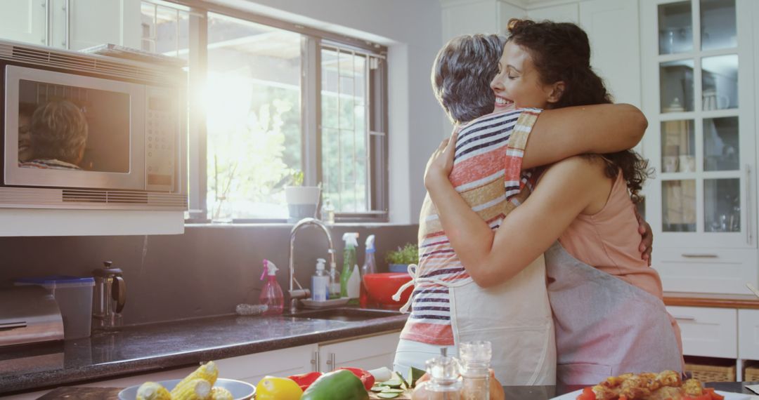 Two Women Hugging in a Bright Kitchen with Fresh Vegetables - Free Images, Stock Photos and Pictures on Pikwizard.com