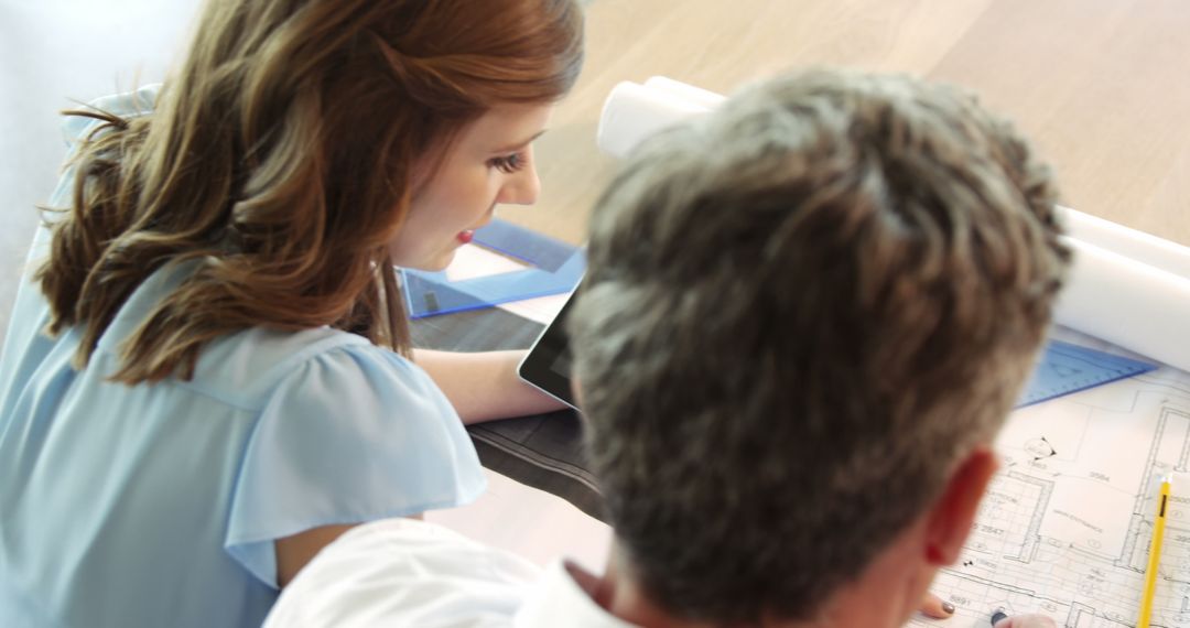 High Angle View of Colleagues Discussing Office Blueprint