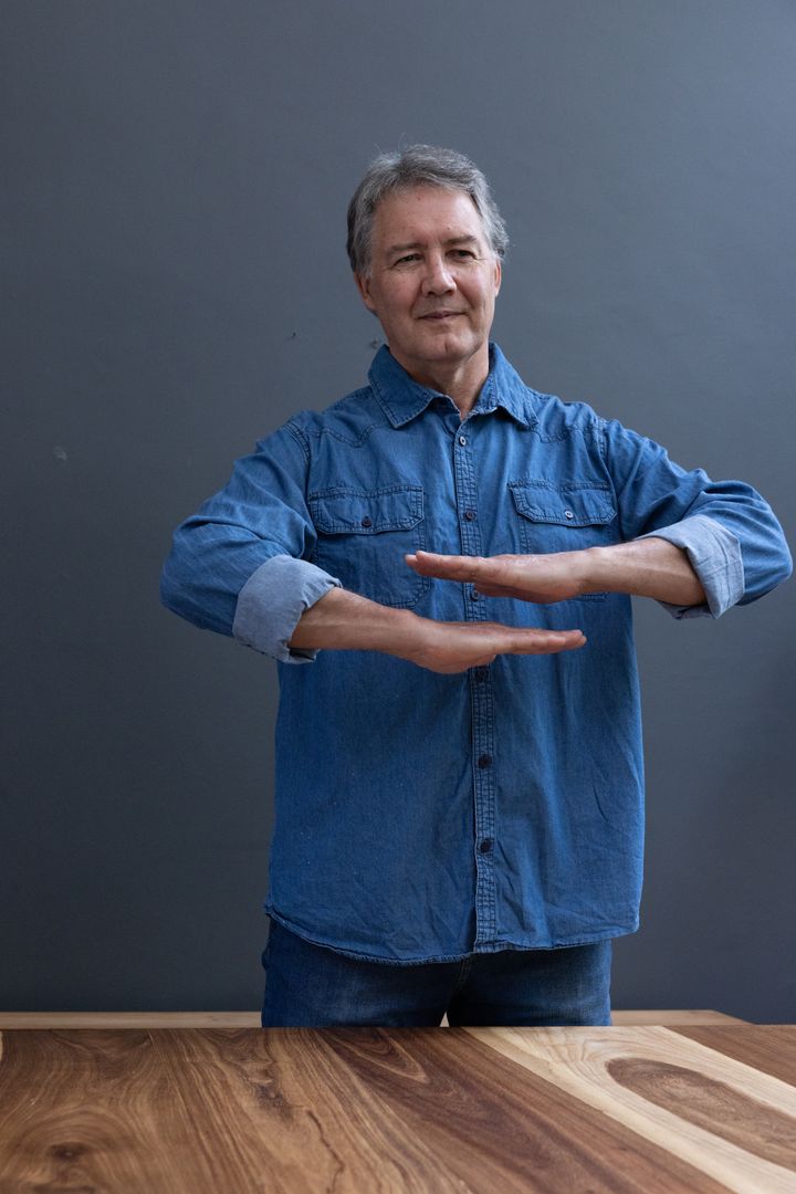 Senior Man Contemplating Wood Grain with Balanced Gesture