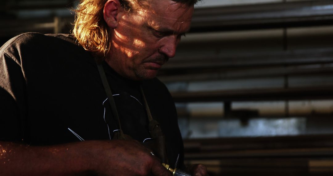 Focused Craftsman Working with Metal in Dimly Lit Workshop - Free Images, Stock Photos and Pictures on Pikwizard.com