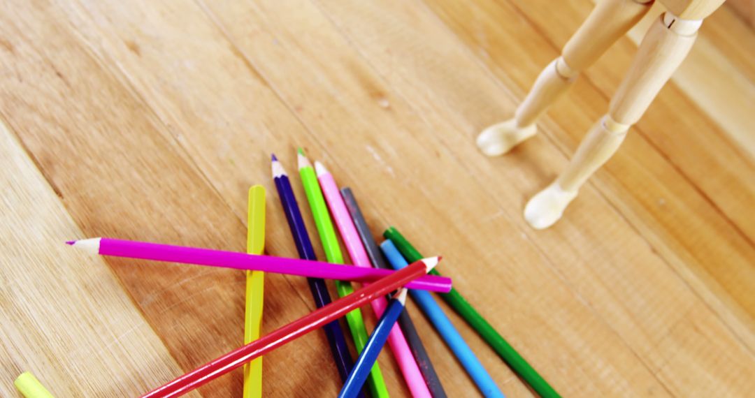 Colorful Pencils on Wooden Desk with Mannequin Standing - Free Images, Stock Photos and Pictures on Pikwizard.com