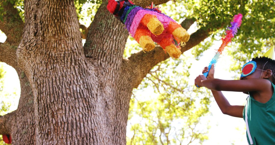 Young Boy Enthusiastically Hitting Colorful Piñata Outdoors - Free Images, Stock Photos and Pictures on Pikwizard.com