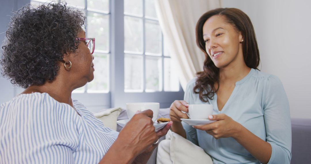 A joyful elderly African American woman enjoys tea and conversation with her daughter at home. - Free Images, Stock Photos and Pictures on Pikwizard.com