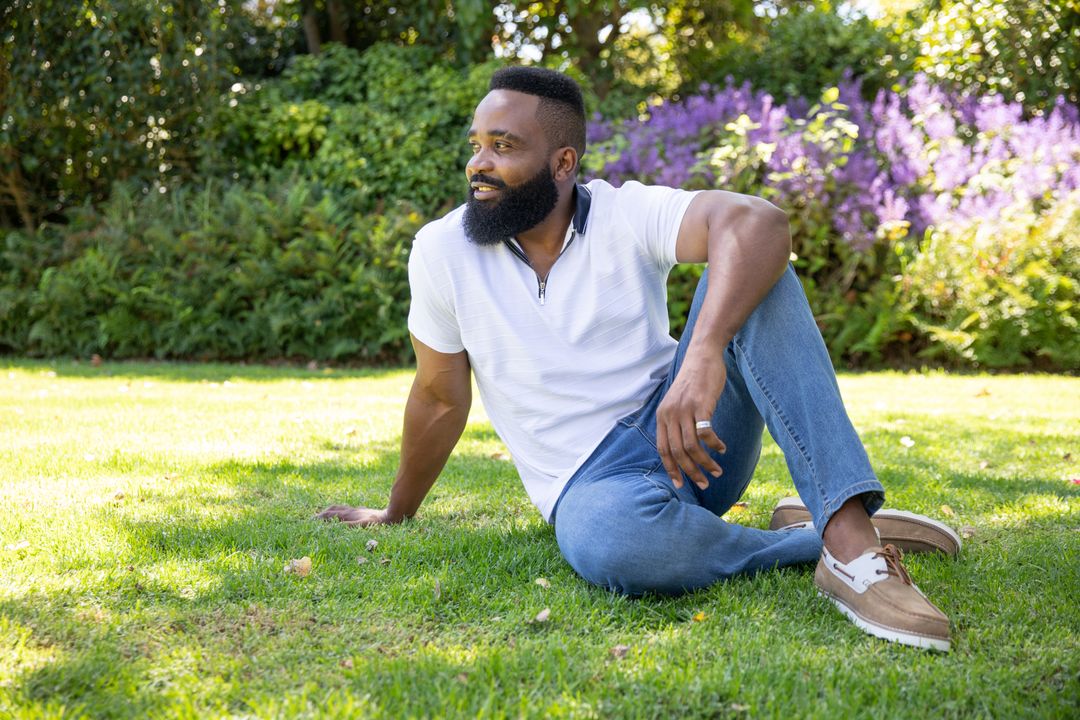 Man Relaxing on Grass in Sunny Park Sitting Thoughtfully