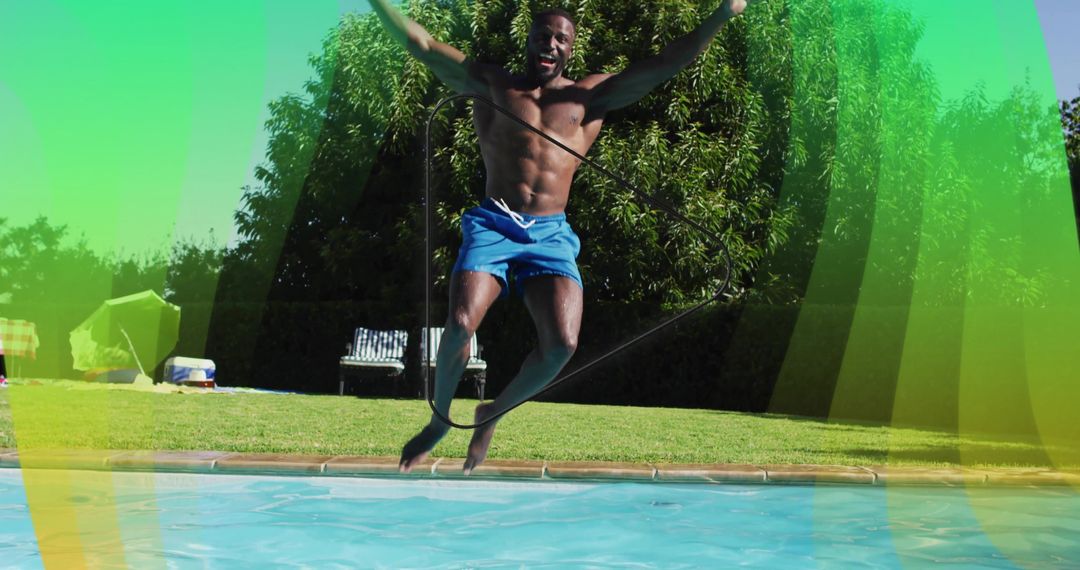 Shirtless man jumping into pool midair with rope backyard summer fitness and joy