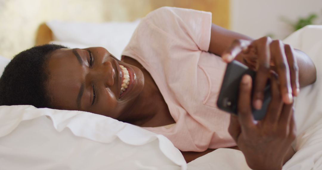 Joyful Woman Relaxing in Bed Using Smartphone