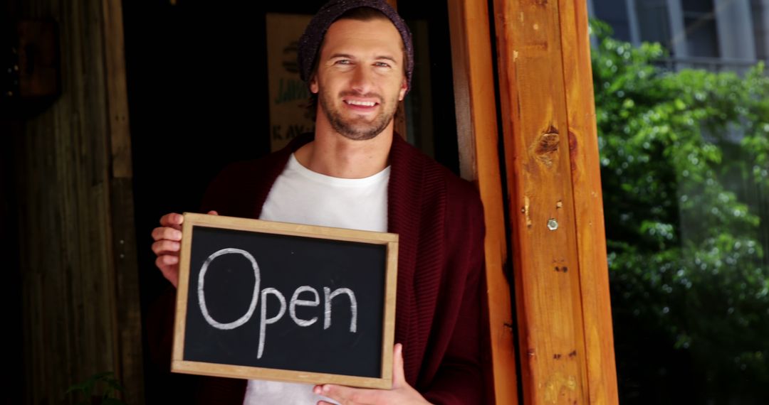 Smiling Business Owner Welcoming with Open Sign at Cafe Entrance