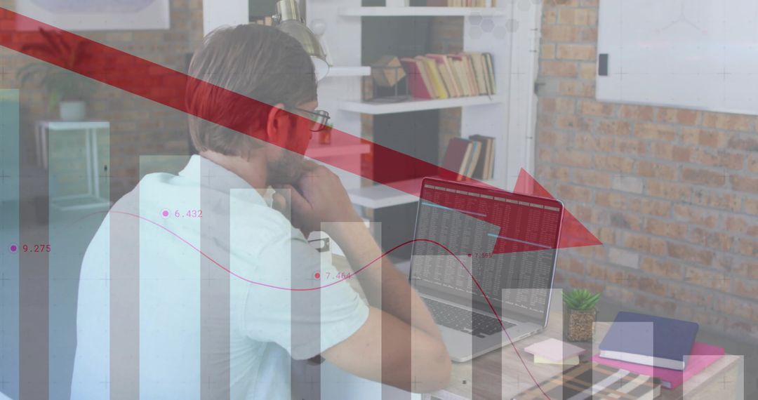 Analyst studying market downturn on laptop with red downward arrow and data charts