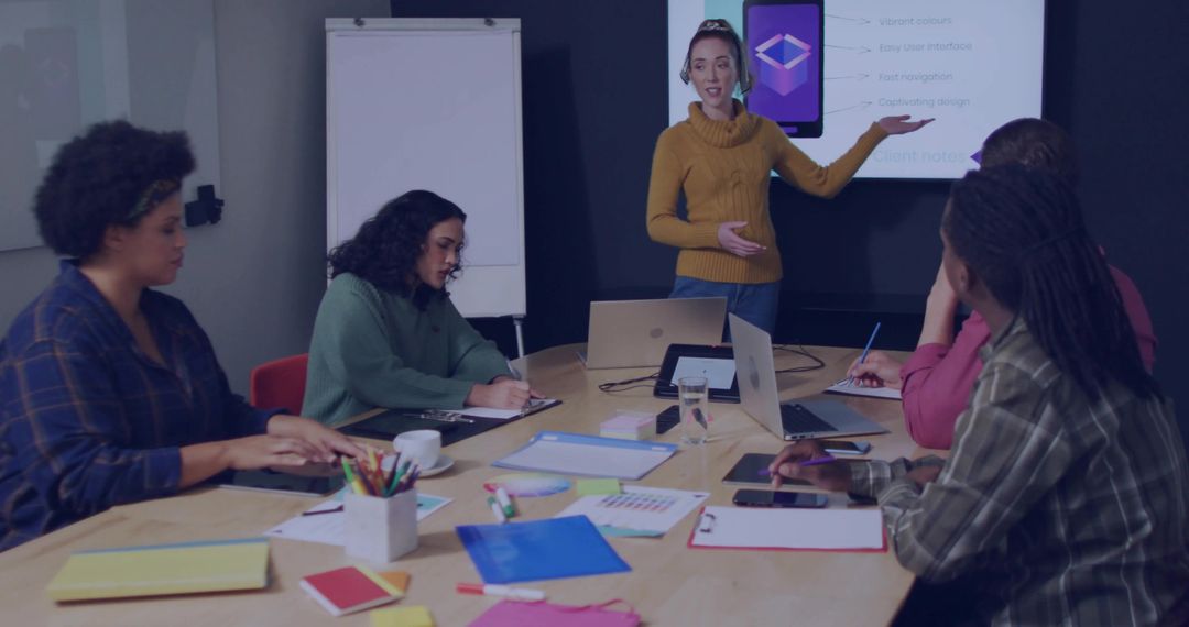 Woman leading presentation in modern boardroom with diverse team taking notes