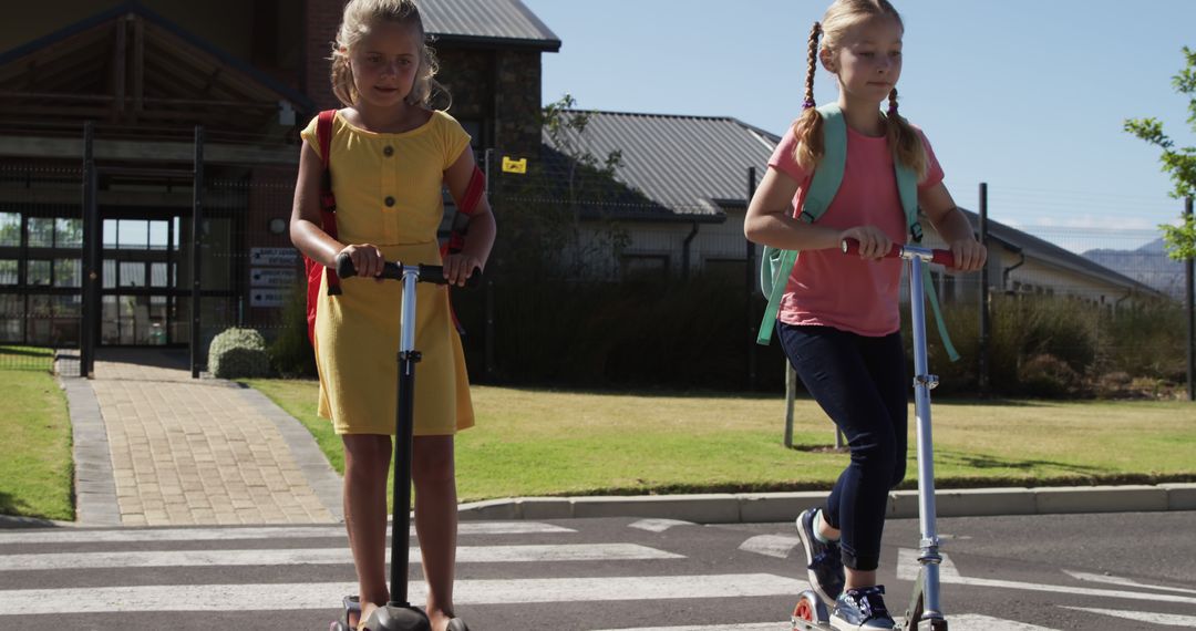 Girls Riding Scooters from School on Sunny Day Crossing Road - Free Images, Stock Photos and Pictures on Pikwizard.com