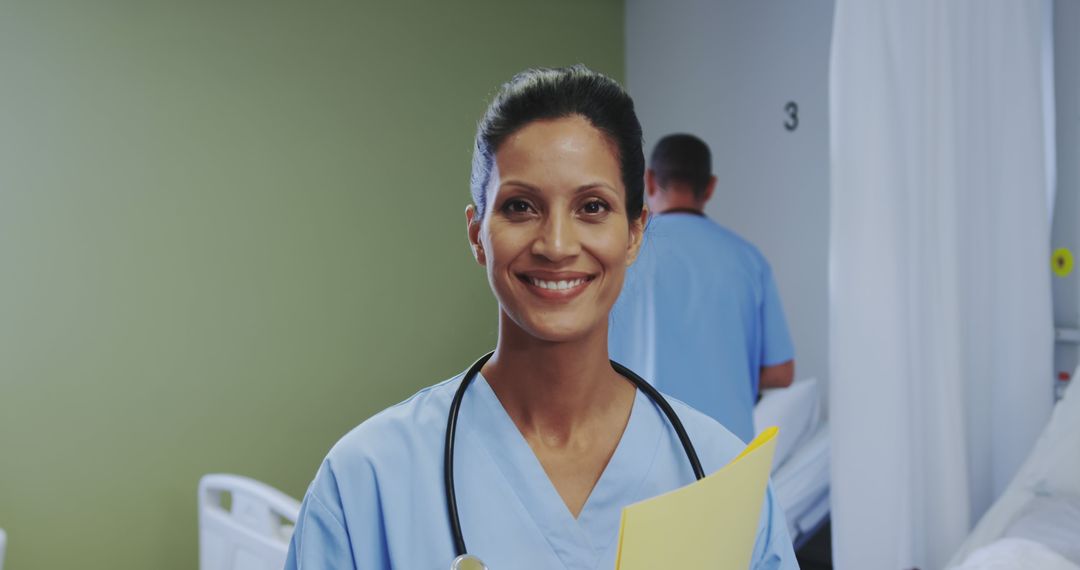 Friendly Nurse Standing in Hospital Ward Holding Clipboard - Free Images, Stock Photos and Pictures on Pikwizard.com