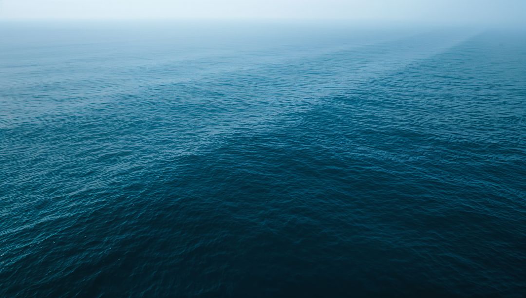 Tranquil Blue Ocean with Gentle Waves under Hazy Sky