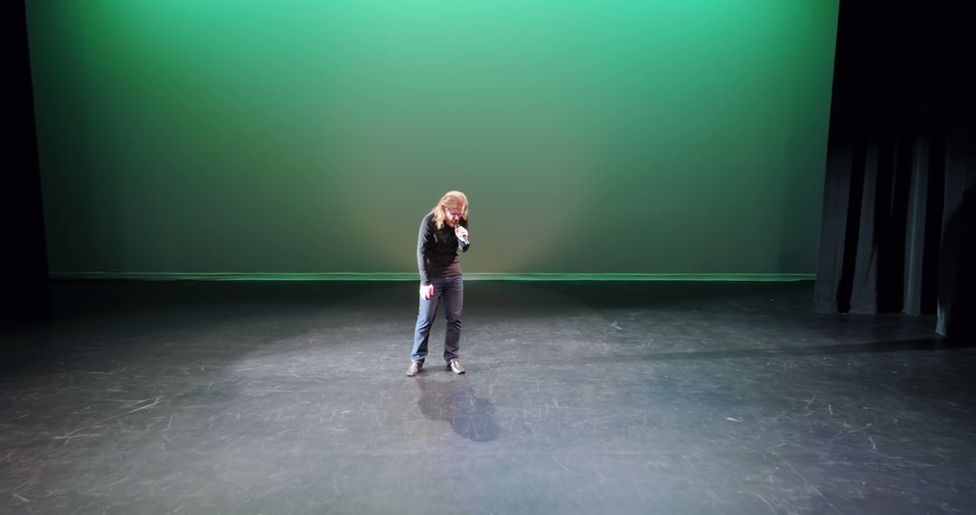 Lonely Performer on Empty Stage with Green Backdrop