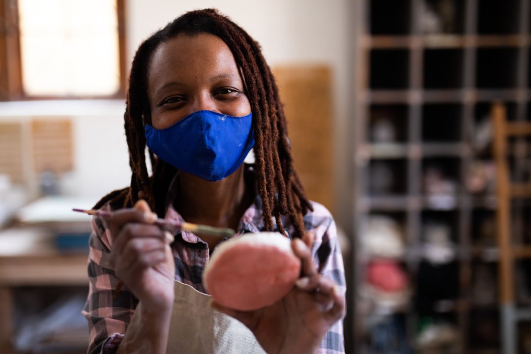 Female Potter Wearing Face Mask Painting Clay in Studio - Free Images, Stock Photos and Pictures on Pikwizard.com