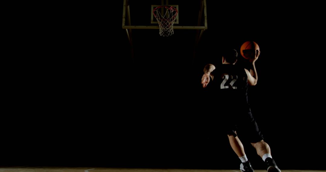 Young Athlete Playing Basketball in Dimly Lit Court - Free Images, Stock Photos and Pictures on Pikwizard.com