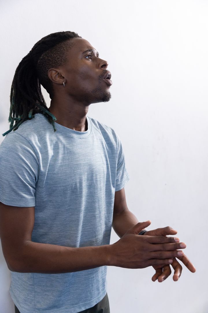 Expressive Man Clapping Against White Wall in Casual Attire